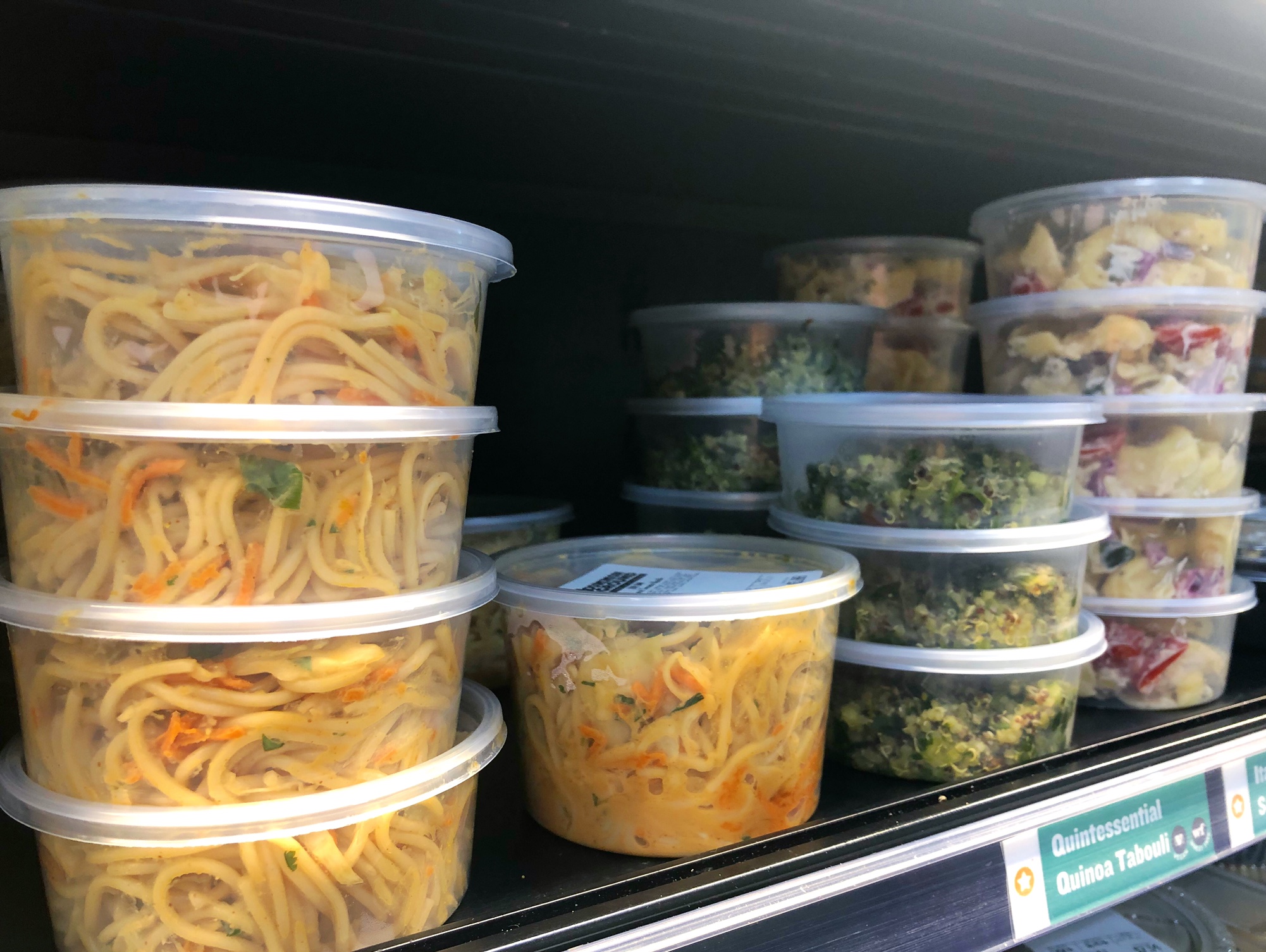 On a metal shelf, there are plastic containers of grab-and-go noodles and soups. Photo by Alyssa Buckley.