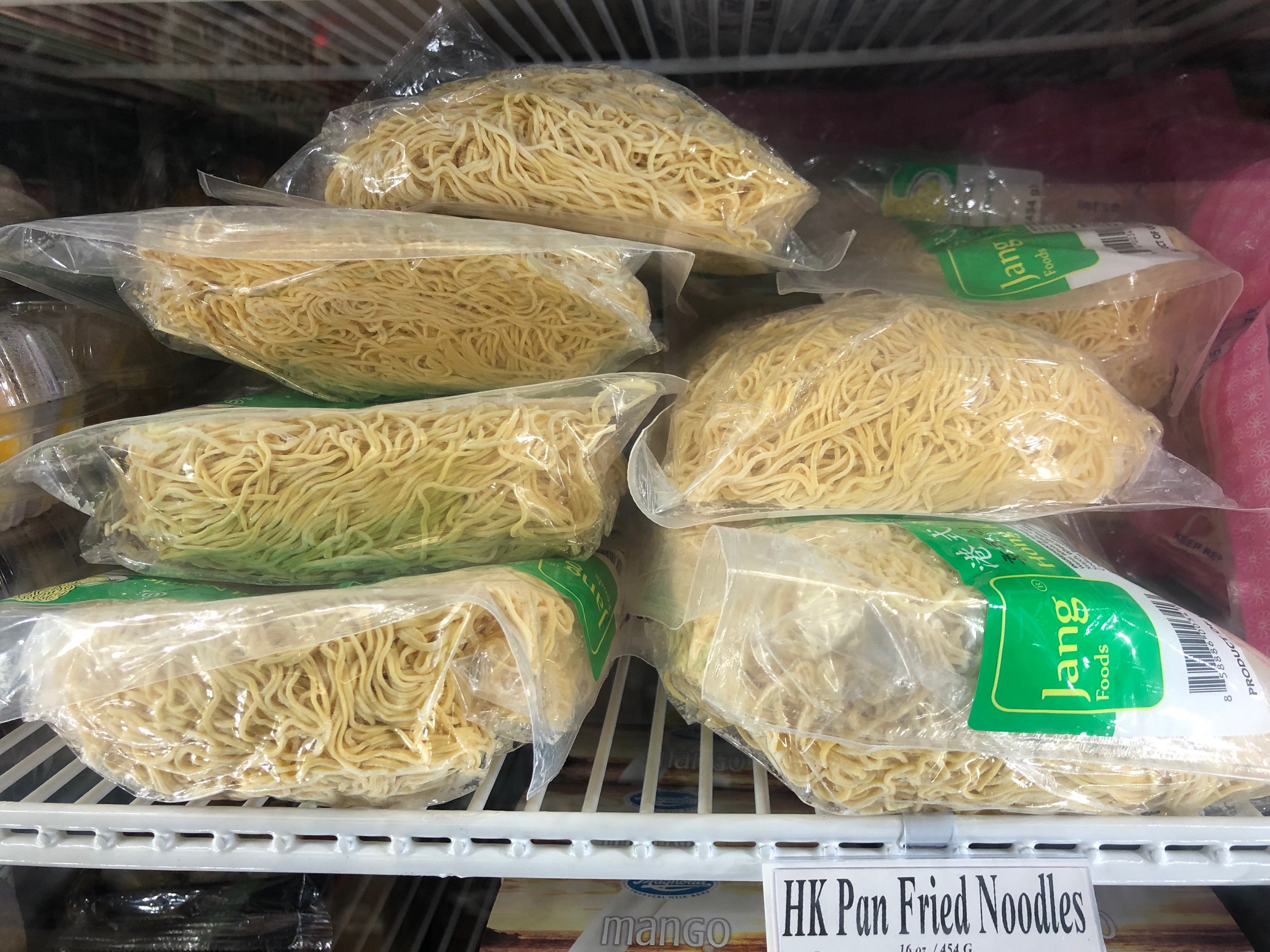 On a white, metal slotted shelf inside a freezer, there are huge bags of noodles. Photo by Alyssa Buckley.
