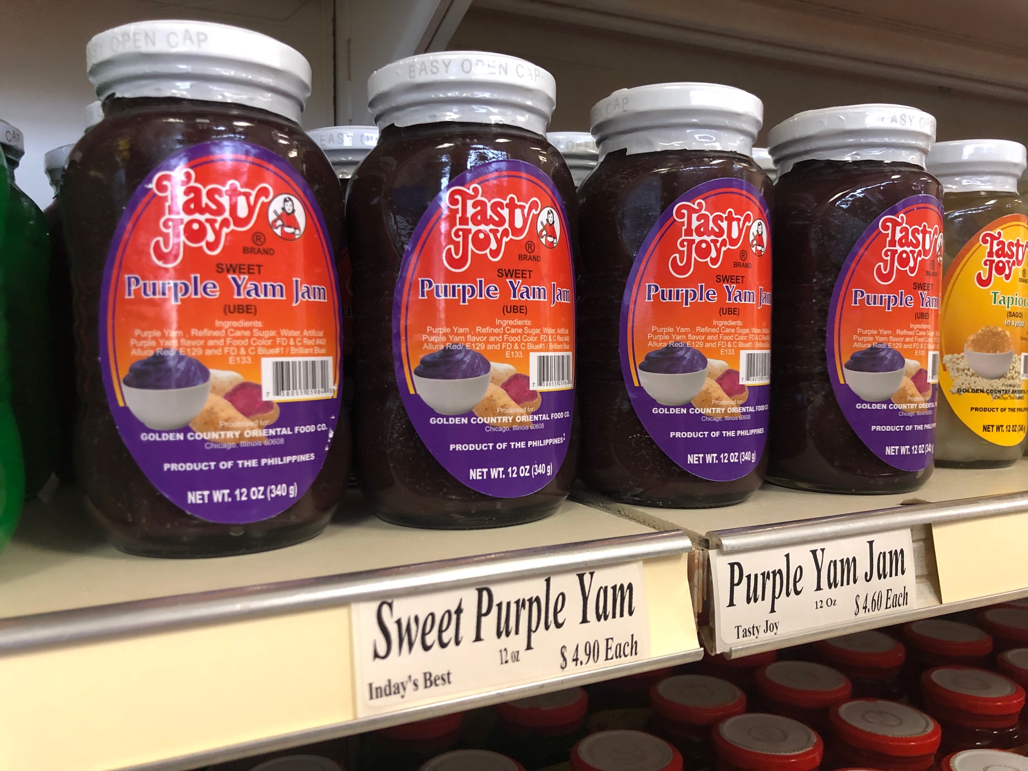 On a shelf several jars of a dark purple jam are forward facing. The little sign below reads 