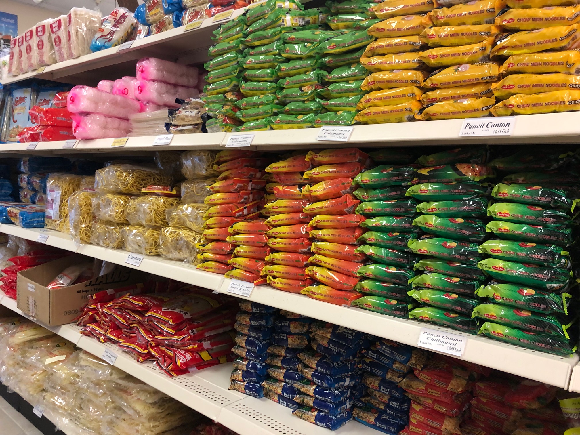 On a shelf inside Maligaya's, there are several stacks of colorful noodle packs. Photo by Alyssa Buckley.