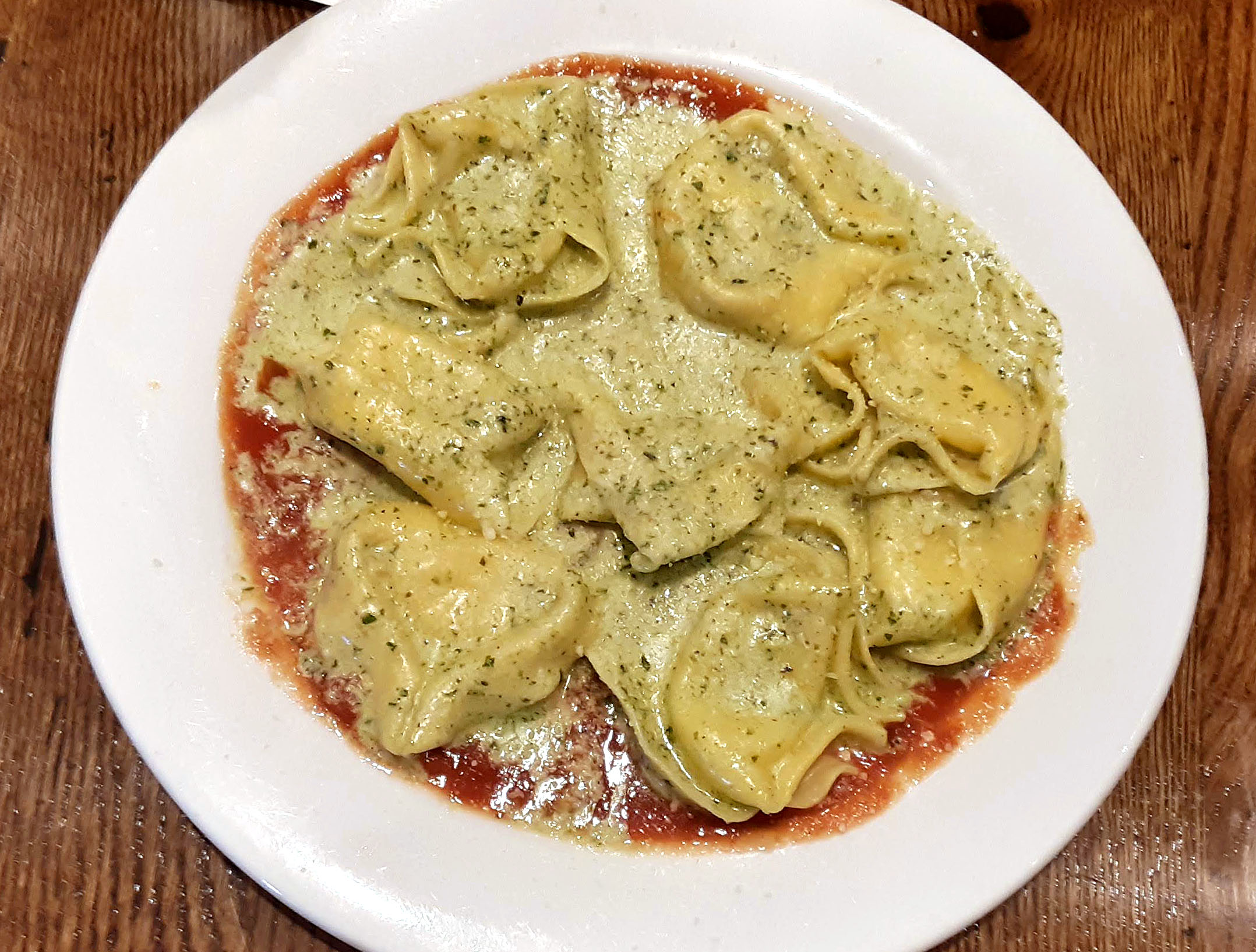 On a large white plate, a ton of ravioli with a white pesto sauce sits. Photo by Paul Young.