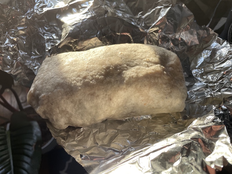 On wrinkled tin foil, there is a large uneaten burrito. Photo by Anthony Erlinger.