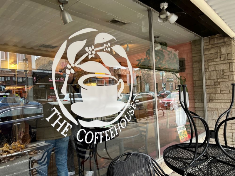 A coffee shop window with a white decal illustration of a coffee cup. It says The Coffeehouse underneath. Photo by Julie McClure.