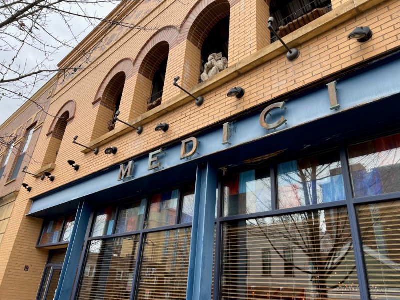 A light brown brick bulding with domed windows across the top. The word Medici is in metal letters on blue framing. Photo by Julie McClure.