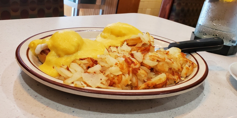 A diner plate of hash browns and eggs benedict.