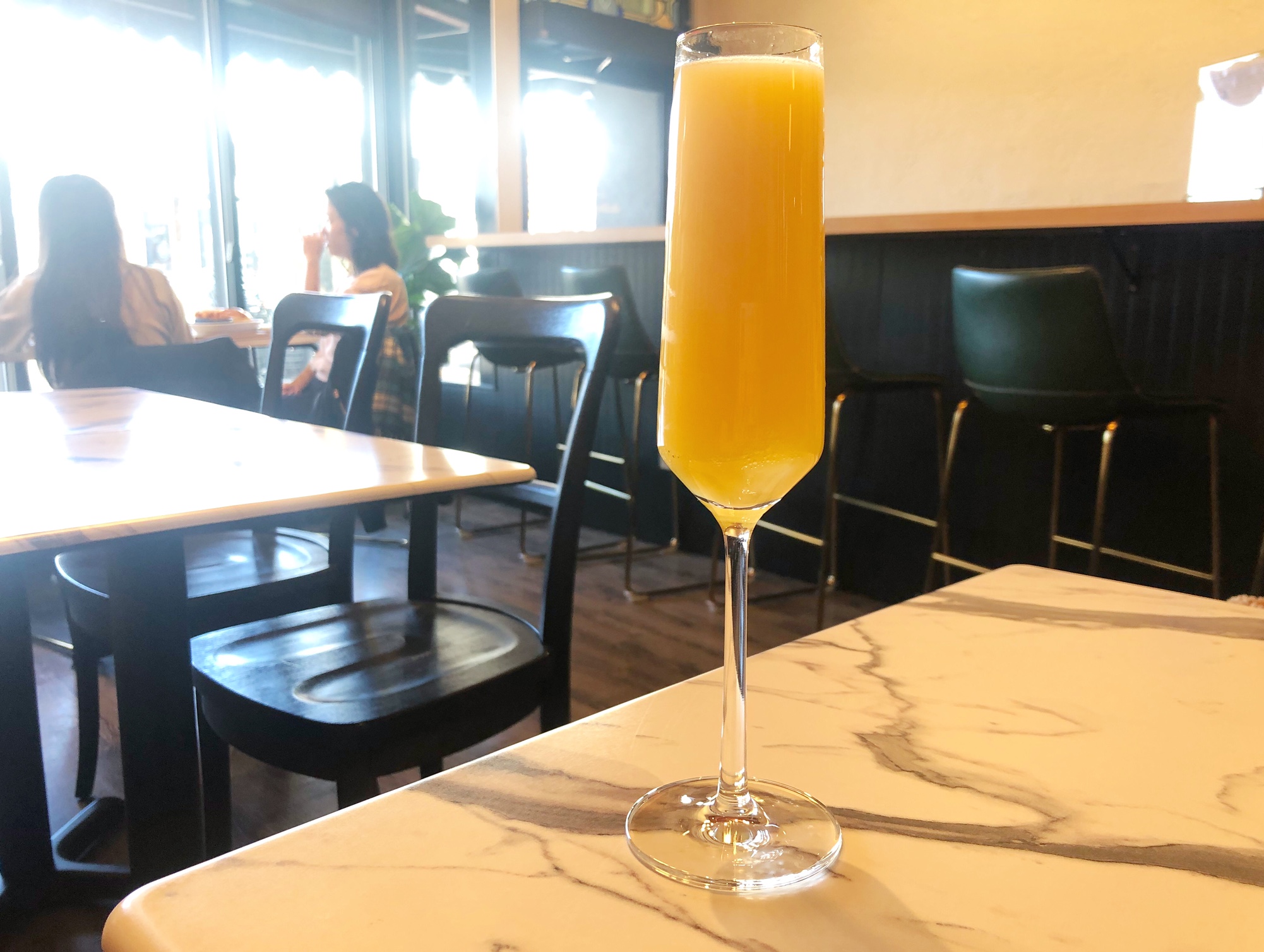 A glass of very orange mimosa sits on a table at The Literary.  Photo by Alyssa Buckley.