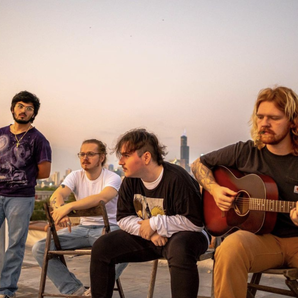 A portrait of the four members of the band. They are on a rooftop in Chicago, the Willis Tower in the background. The band looks off into the distance.