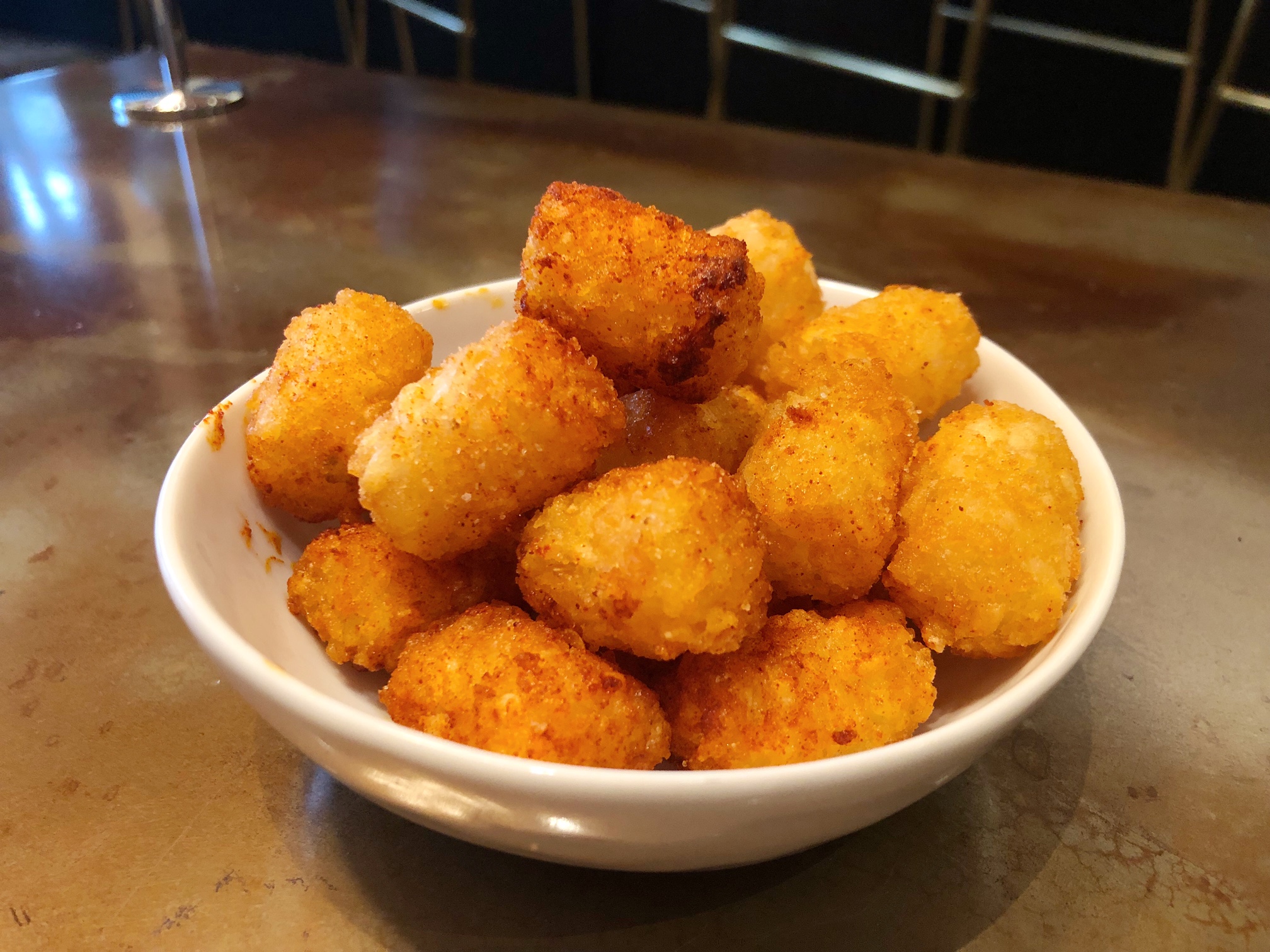 In a shallow white bowl, there is a pile of tots from The Literary in Downtown Champaign.  Photo by Alyssa Buckley.
