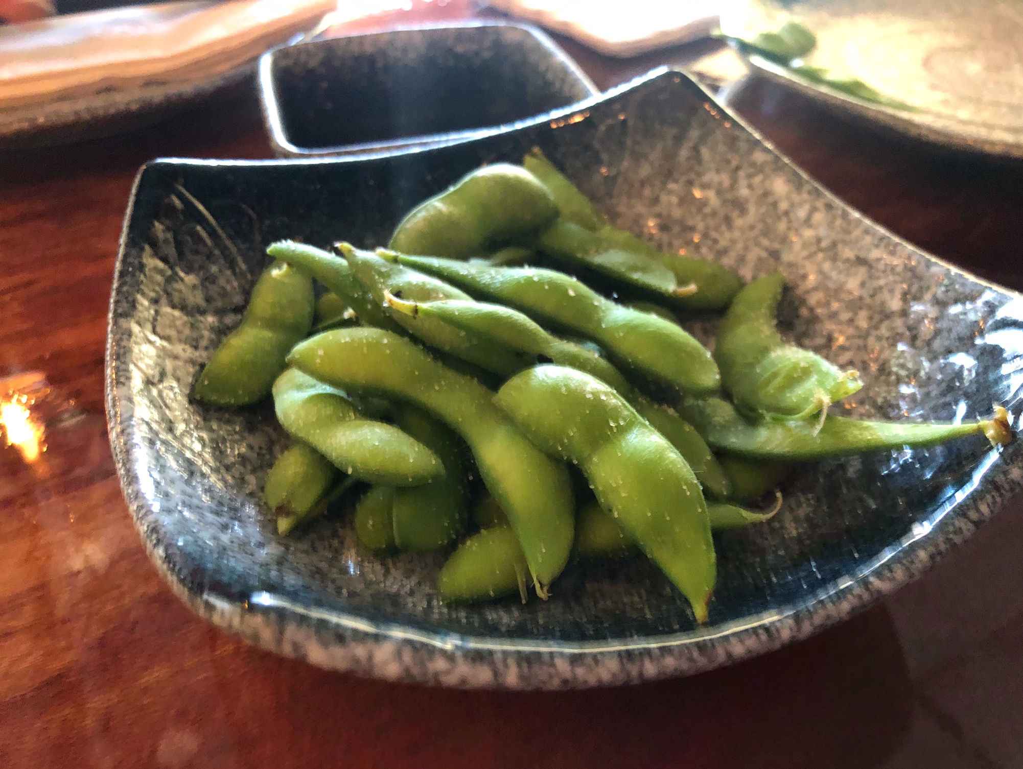 In a textured blue bowl, there is a serving of edamame. Photo by Alyssa Buckley.