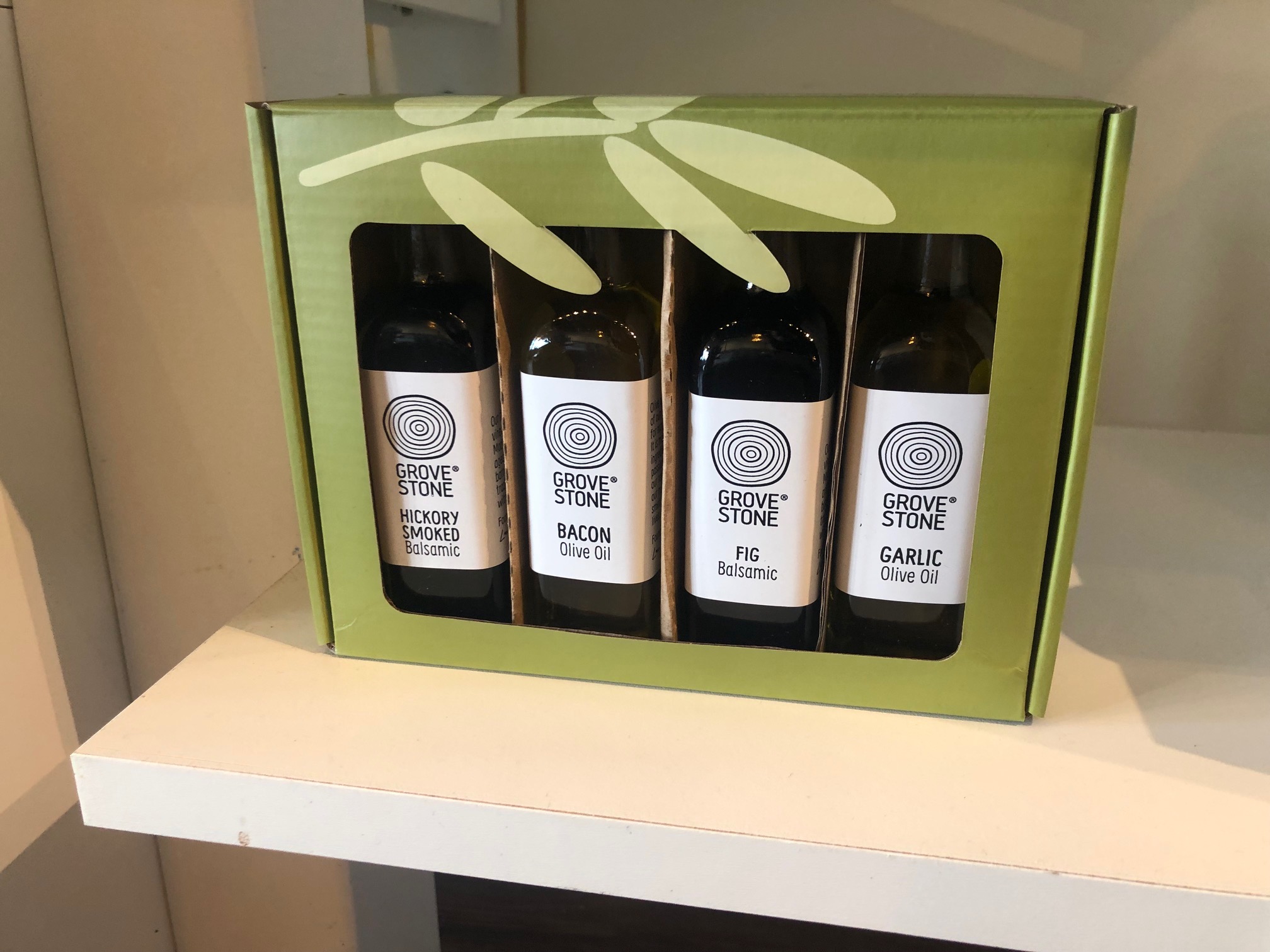 In a green cardboard box, there are four mini bottles of Grovestone olive oil. Photo by Alyssa Buckley.