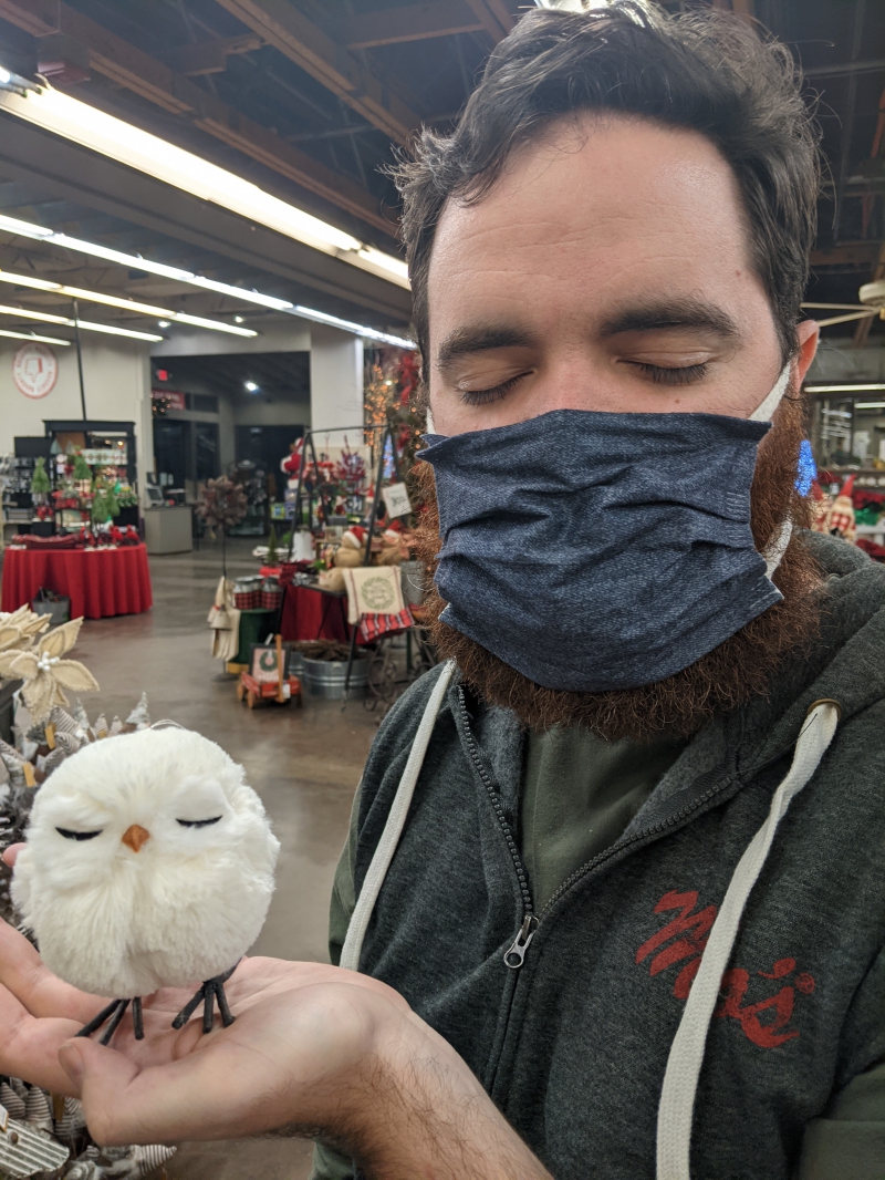 The writer is holding a small, round, white-feathered owl that has its eyes closed. The writer's eyes are also closed. Photo by Andrea Black. 