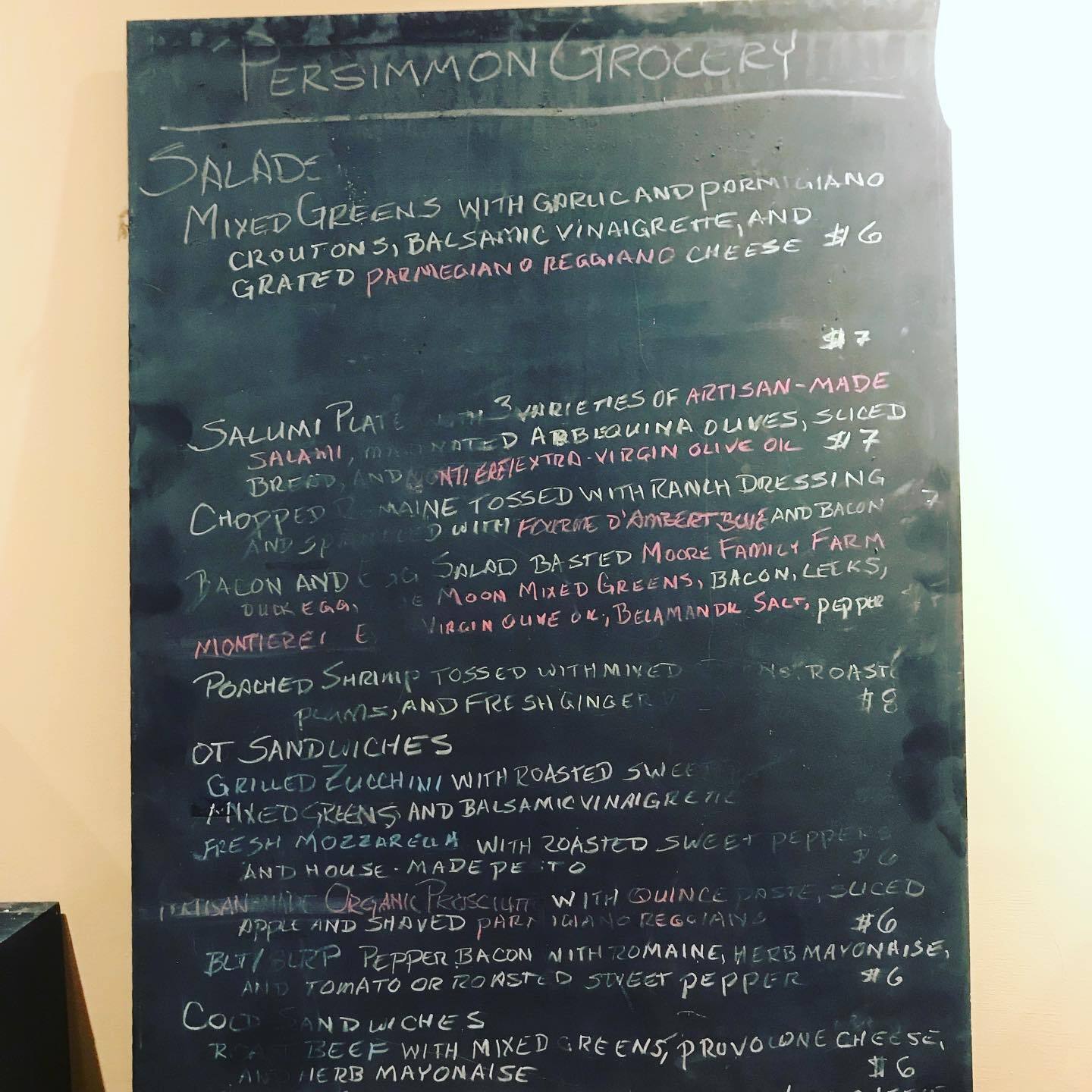 Photo of a chalkboad menu for Persimmon Grocery, including salads and sandwiches. Photo by Thad Morrow. 