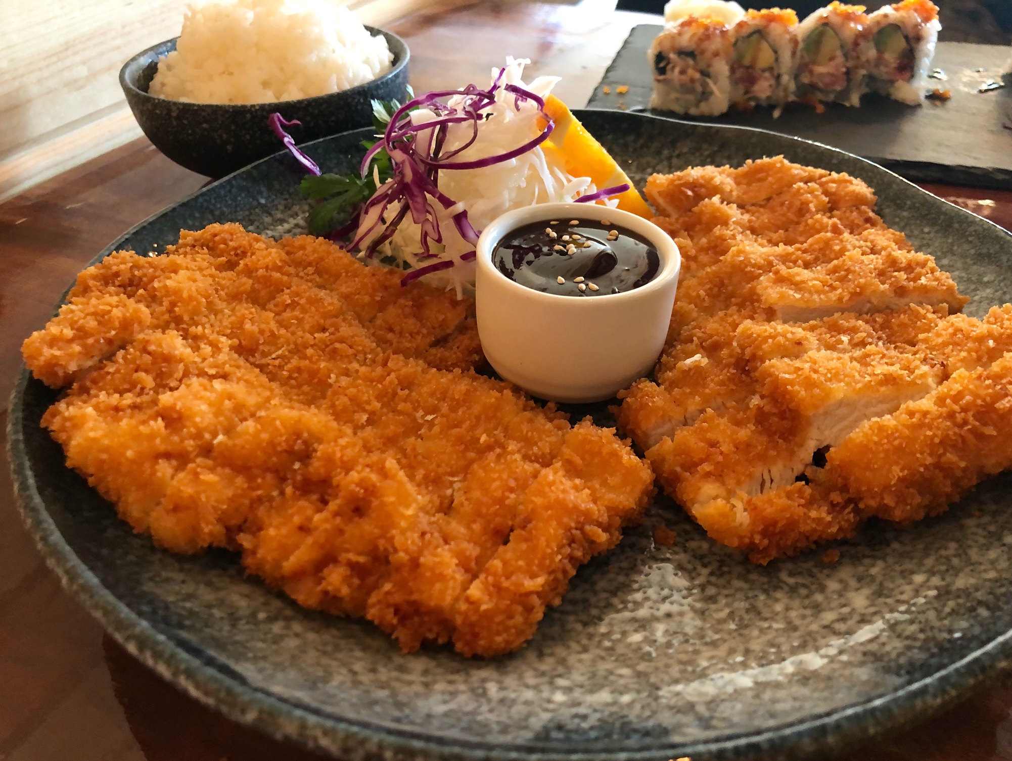 On a gray speckled plate, there are two big pieces of panko-breaded chicken with a small dipping sauce in the middle. Photo by Alyssa Buckley.