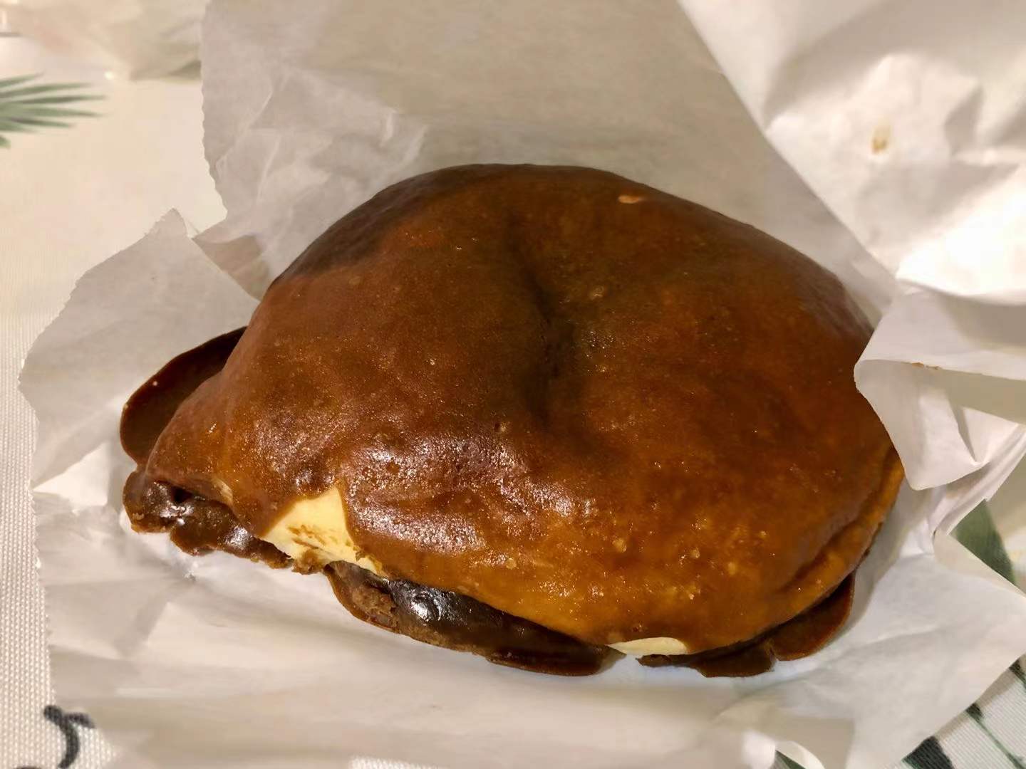 On parchment paper, there is a papparoti coffee bun with a dark brown exterior. Photo by Xiaohui Zhang.