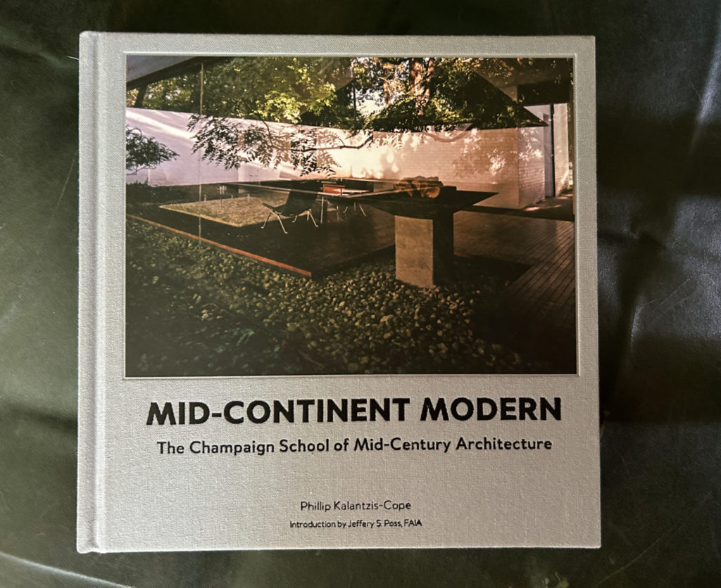 Photo of the cover of a book entitled Mid-Continent Modern: The Champaign School of Mid-Century Architecture by Phillip Kalantzis-Cope. Cover photo is of trees hovering over an a square table.