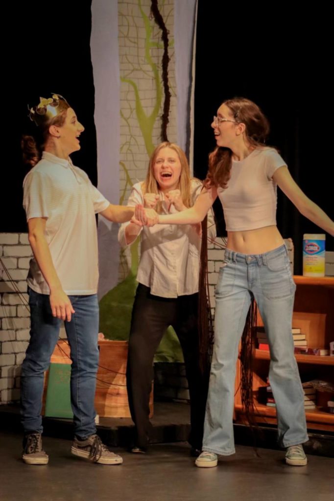 Three young actresses are on stage, one wears a crown.