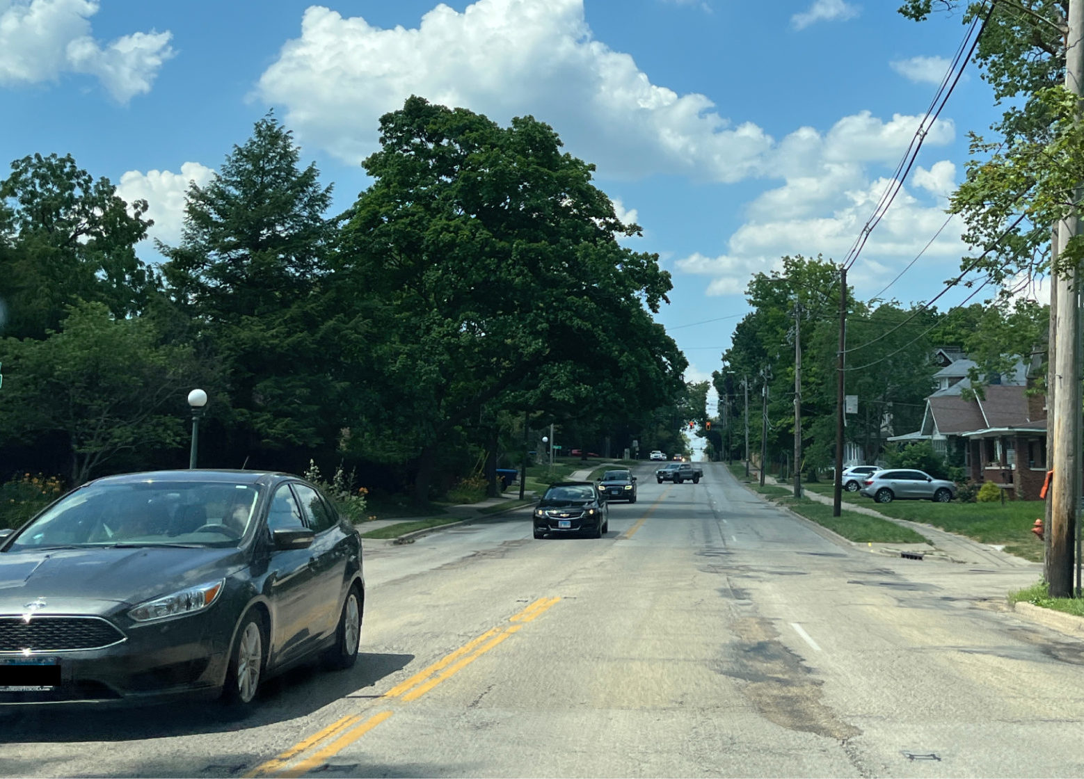 Prospect Avenue in Champaign, facing north. A four lane road is narrow, with many cars in the southbound lanes. The sky is blue and the trees are green; there are no other cars in the northbound lanes.