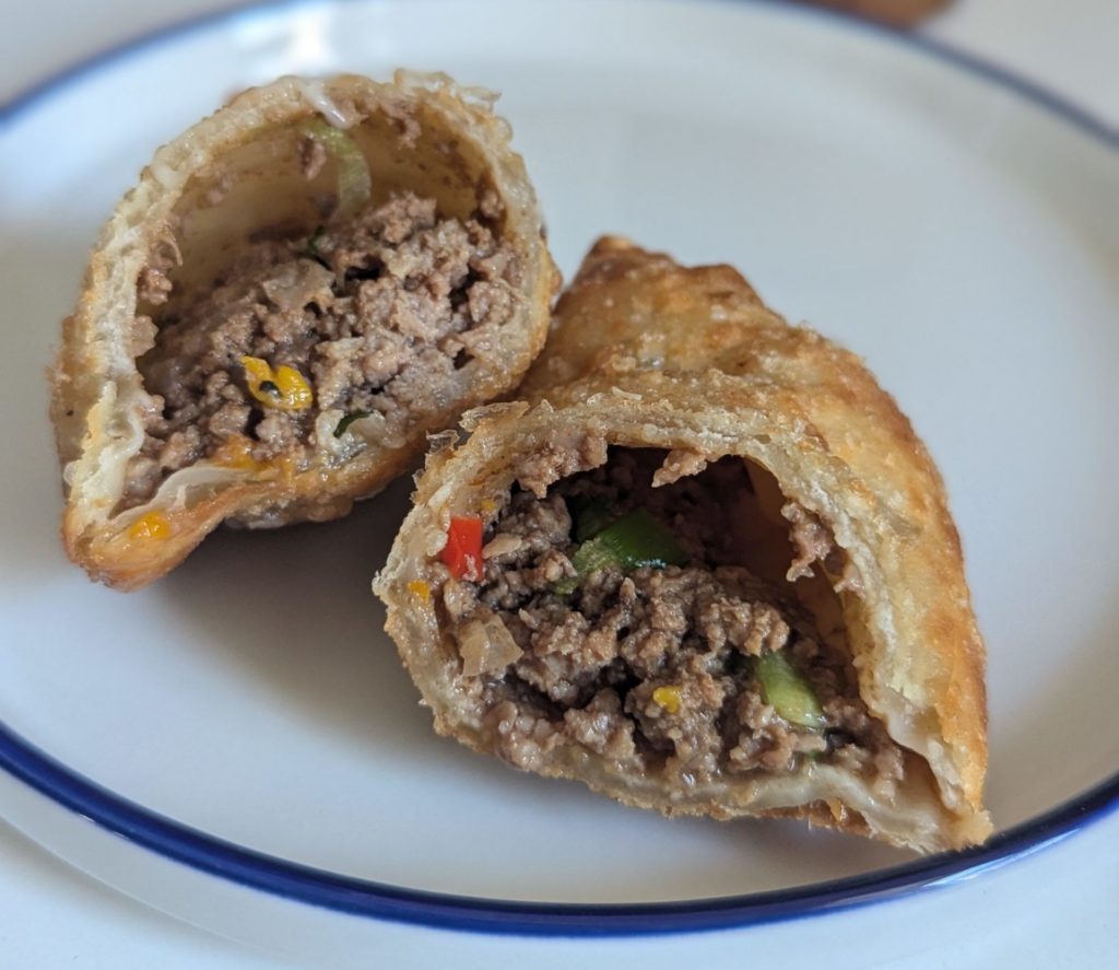 A sliced open empanada with beef and vegetables.
